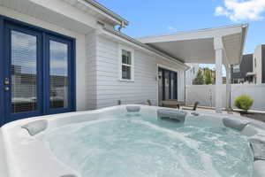 View of patio featuring a hot tub, outdoor dining and additional parking spaces