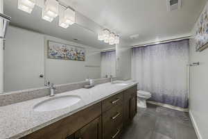 Full basement bathroom with double vanities and quartz countertops