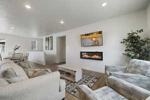 Living room featuring a glass covered fireplace, baseboards, recessed lighting, and wood finished floors