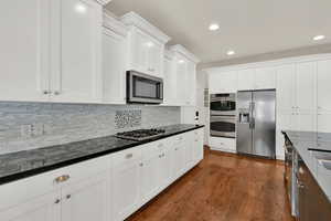 Kitchen featuring white cabinetry, stainless steel appliances, dark wood finished floors, recessed lighting, and decorative backsplash