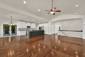 Unfurnished living room featuring lofted ceiling, dark wood-style flooring, a chandelier, a ceiling fan, and recessed lighting