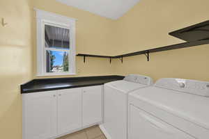 Washroom featuring light tile patterned floors and washer and clothes dryer