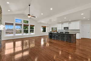 Unfurnished living room featuring dark wood-style floors, a fireplace, ceiling fan, a chandelier, and recessed lighting