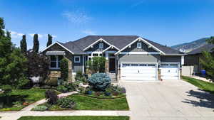 Craftsman house featuring stone siding, board and batten siding, driveway, an attached garage, and a front yard