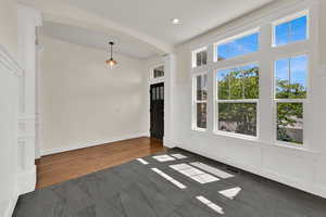 Foyer entrance featuring arched walkways, ornate columns, recessed lighting, dark wood-type flooring, and dark carpet