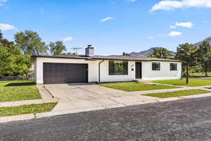 Ranch-style home featuring a garage, a front lawn, a chimney, and driveway