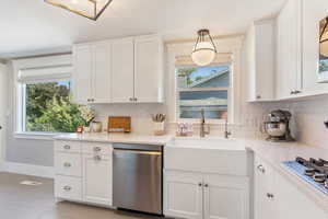 Kitchen featuring stainless steel appliances, decorative backsplash, healthy amount of natural light, and white cabinets