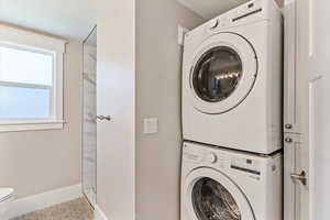 Washroom featuring stacked washer / drying machine and a textured ceiling