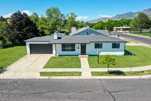 View of front of property featuring a front lawn, a mountain view, an attached garage, and concrete driveway