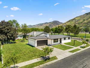 Single story home featuring an attached garage, a mountain view, driveway, a front lawn, and stucco siding