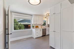 Kitchen with stainless steel dishwasher, healthy amount of natural light, white cabinetry, and light countertops