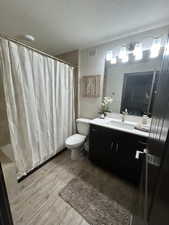 Bathroom featuring wood finished floors, vanity, a textured ceiling, and shower / bath combo