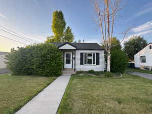View of front of home with a front yard, roof with shingles, and a chimney