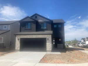 View of front of home with a garage, driveway, stone siding, and board and batten siding