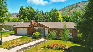 View of front of house with a mountain view, a garage, a front lawn, and concrete driveway