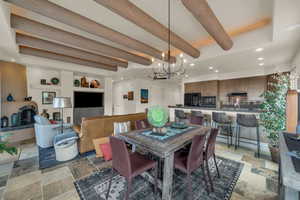Dining room featuring stone tile flooring, a chandelier, recessed lighting, and beam ceiling