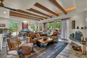 Living room featuring plenty of natural light, beamed ceiling, recessed lighting, stone tile floors, and a chandelier