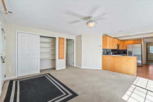 Kitchen with stainless steel appliances, ceiling fan, light colored carpet, a peninsula, and open floor plan