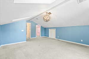 Bonus room with carpet flooring, a chandelier, and a skylight