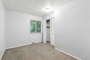 Unfurnished bedroom featuring carpet, a closet, and a textured ceiling