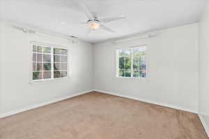 Empty room featuring carpet flooring and a ceiling fan