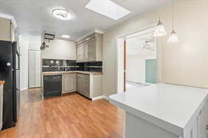 Kitchen with black appliances, a skylight, tasteful backsplash, and gray cabinetry