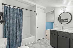 Bathroom with shower / bath combo, vanity, and a textured ceiling