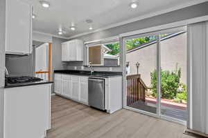 Kitchen featuring light wood-style floors, crown molding, white cabinets, stainless steel appliances, and recessed lighting