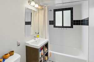 Bathroom with shower / tub combo with curtain, vanity, and a chandelier