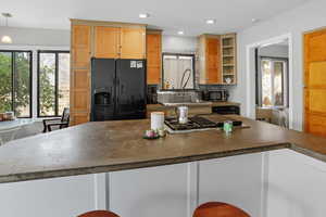 Kitchen with stainless steel appliances, healthy amount of natural light, dark countertops, open shelves, and recessed lighting