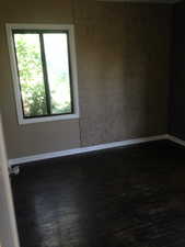 Spare room with dark wood-style flooring and baseboards