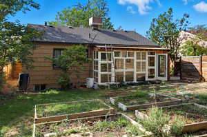 Rear view of property with a shingled roof, a garden, a sunroom, and a chimney