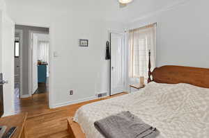 Bedroom with light wood-style flooring, multiple windows, and a ceiling fan