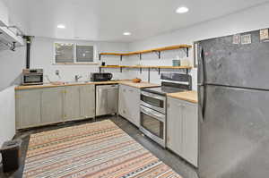 Kitchen featuring appliances with stainless steel finishes, open shelves, and recessed lighting