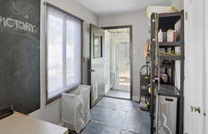 Doorway to outside featuring stone tile flooring and baseboards