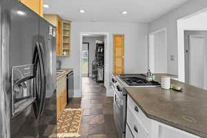 Kitchen with appliances with stainless steel finishes, recessed lighting, stone tile floors, and a kitchen island