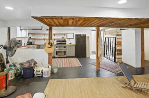Kitchen with finished concrete flooring, black appliances, recessed lighting, open shelves, and wood ceiling