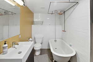 Bathroom featuring vanity, tile walls, and a combined bath / shower with freestanding tub