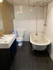 Full bathroom with vanity, tile walls, and a combined bath / shower with freestanding tub