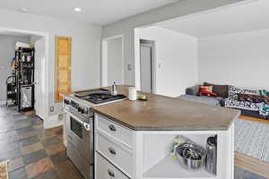 Kitchen with high end range, a center island, white cabinetry, recessed lighting, and open floor plan