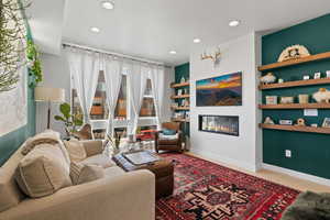 Living area with a glass covered fireplace, recessed lighting, and built in shelves
