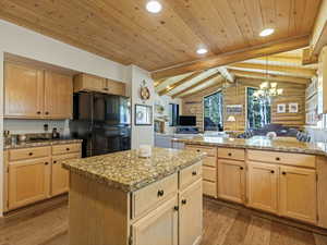 Kitchen with freestanding refrigerator, rustic walls, wood ceiling, light wood-style floors, and light brown cabinetry