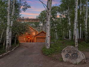 View of front of property featuring dirt driveway and a garage