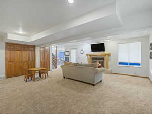 Living area featuring carpet flooring, stairway, a tiled fireplace, and recessed lighting