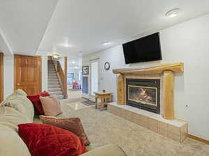 Carpeted living area with stairs and a fireplace