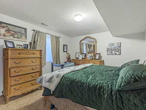 Bedroom featuring light carpet and a textured ceiling