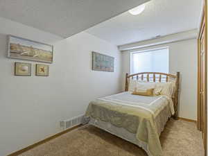 Carpeted bedroom with a textured ceiling and baseboards