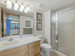 Full bath with vanity, a stall shower, tile patterned flooring, and a textured ceiling