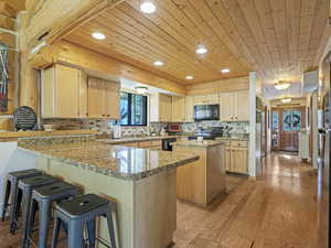 Kitchen featuring black appliances, wooden ceiling, a peninsula, a kitchen island, and recessed lighting