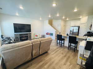 Living room featuring light wood-type flooring, recessed lighting, and stairway